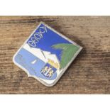 An Art Deco enamel and base metal Ajaccio Corsican brooch, decorated with a yacht within a