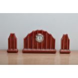A 20th century continental ceramic clock garniture, red glaze, circular dial with Arabic numerals,