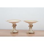 A pair of porcelain cake stands, unmarked, with heightened gilt and floral design, the columns