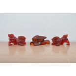 A pair of early 20th century cherry amber temple dogs, 8.5cm & 9cm in length, together with an amber