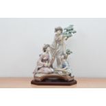 A Lladro ceramic figural group, two Japanese women (one with a restored thumb) and a child playing