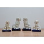 Two pairs of 19th century ceramic Staffordshire poodles, the larger examples with one puppy each,
