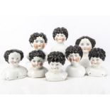 Eight china shoulder heads, all with blue painted eyes and black hair, the largest -8 ¼in. (21cm.)