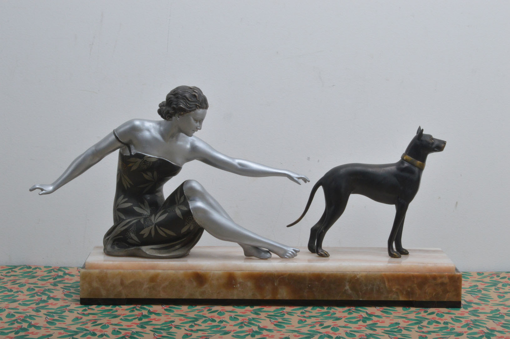 An Art Deco and later painted spelter figure of a lady and a Doberman dog after Uriano, presented on