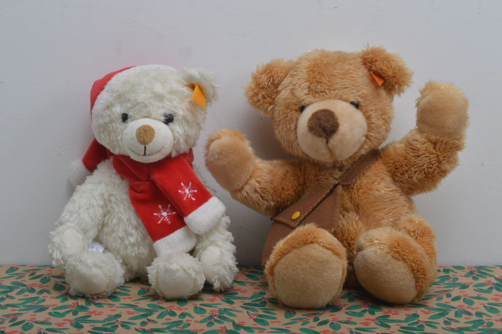 Two modern Steiff yellow tag Teddy bears, one white bear wearing Christmas hat and scarf, the