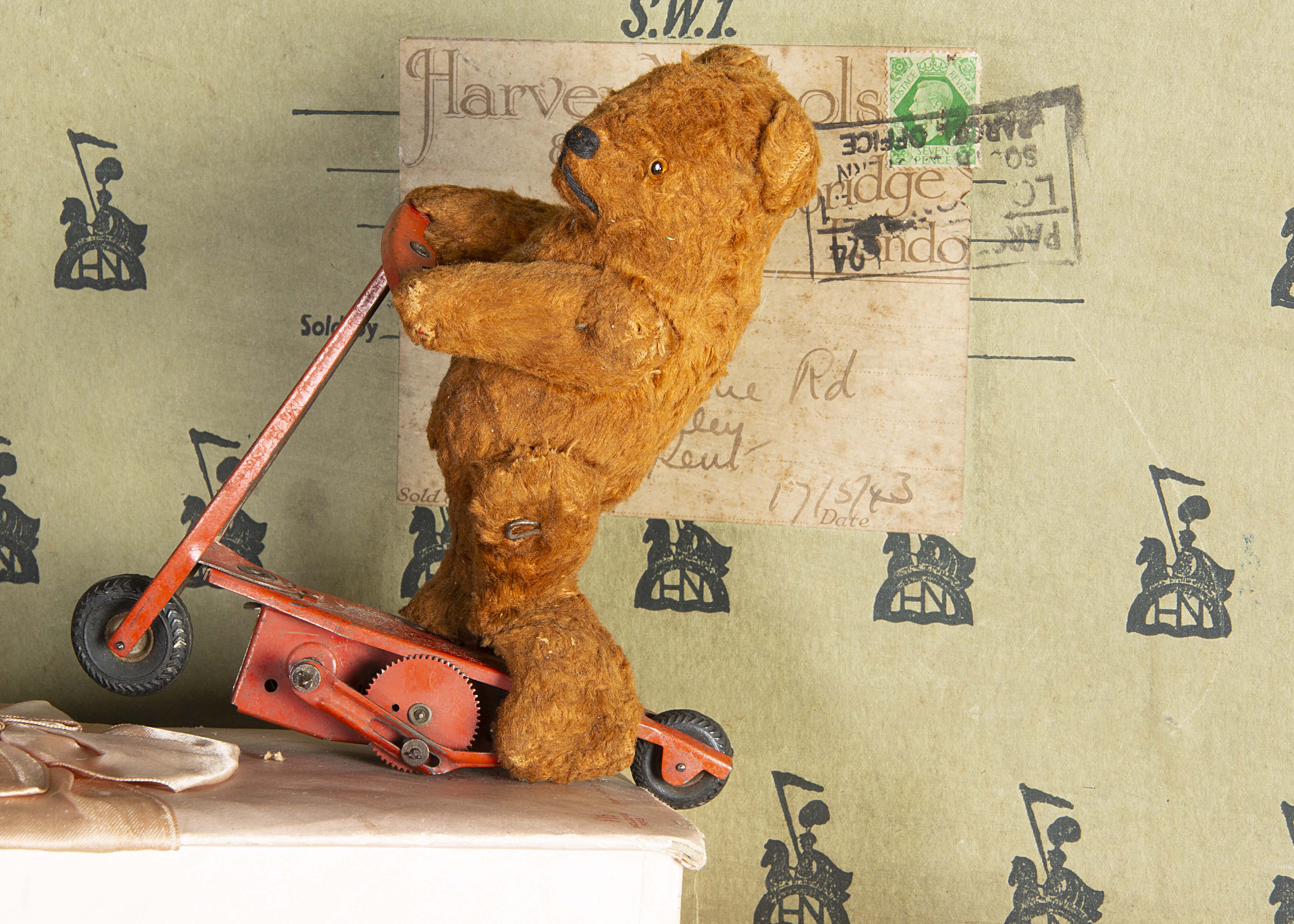 A Fehn Wolf & Co clockwork Teddy Bear on scooter 1950s, with brown artificial-silk plush, orange and