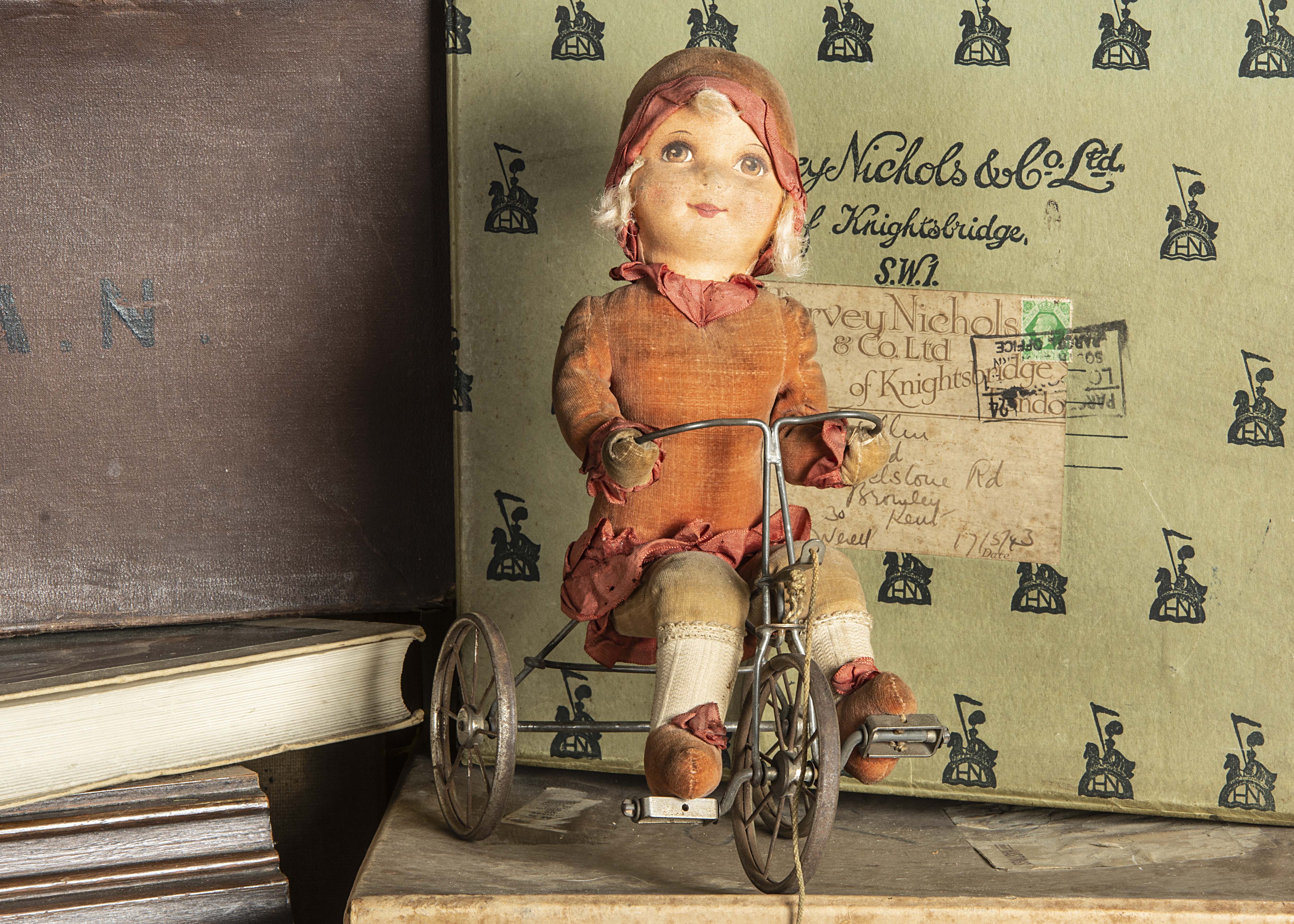 A Dean’s Rag Book Co girl doll riding a tricycle 1930s, with brown eyed printed face, blonde