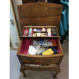 A wooden lift up sewing box on turned out legs wit