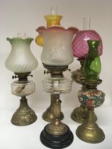 A collection of five brass oil lamps with coloured