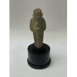 A small carved stone ushabti figure with stand.