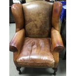 A tan leather wing armchair.