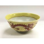 A Chinese bowl decorated with a red dragon on a ye