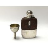 A silver hip flask and a small funnel.