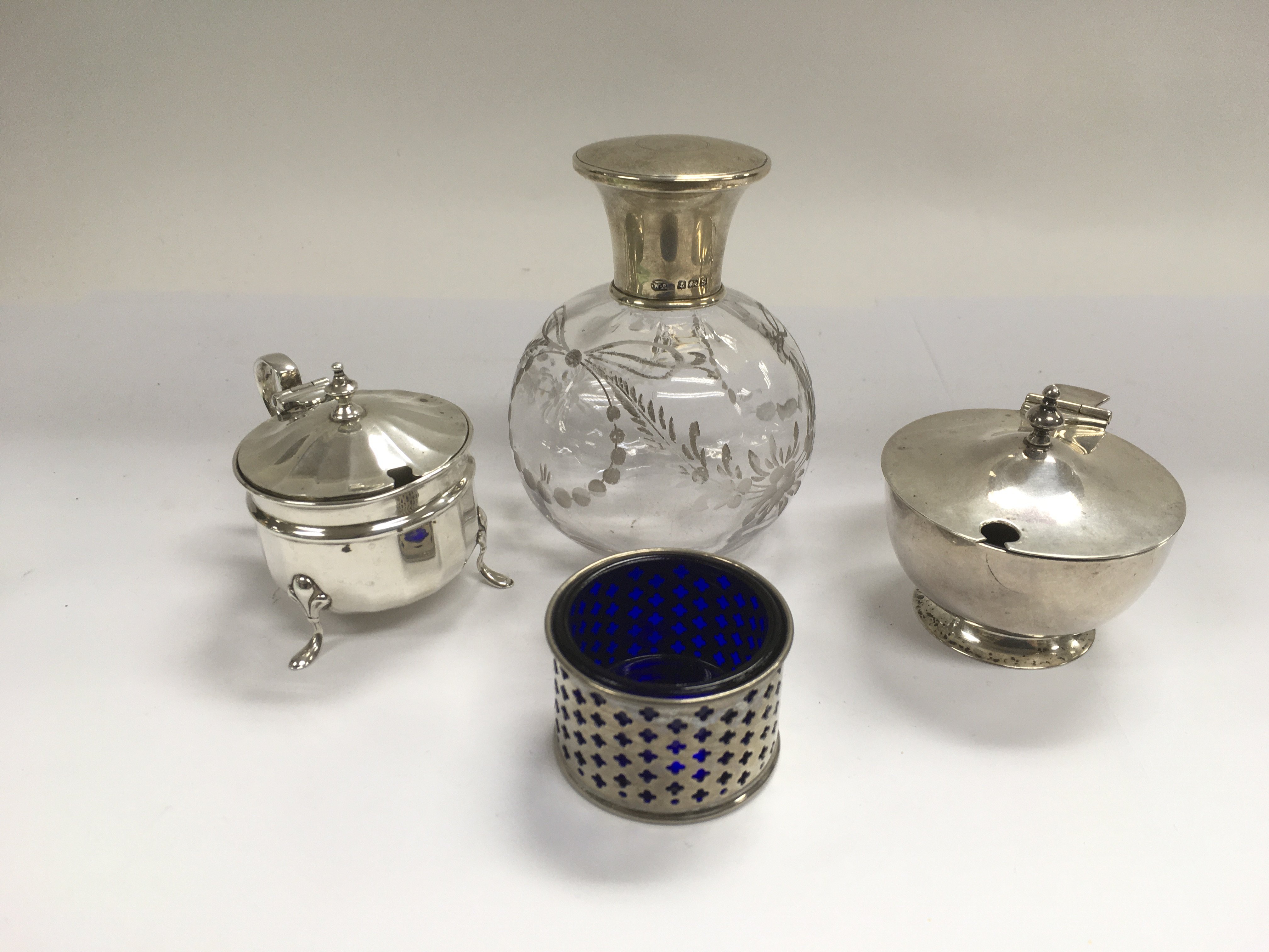 A silver topped perfume bottle and three silver co