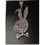 A 9ct white gold pink stoned playboy pendant.