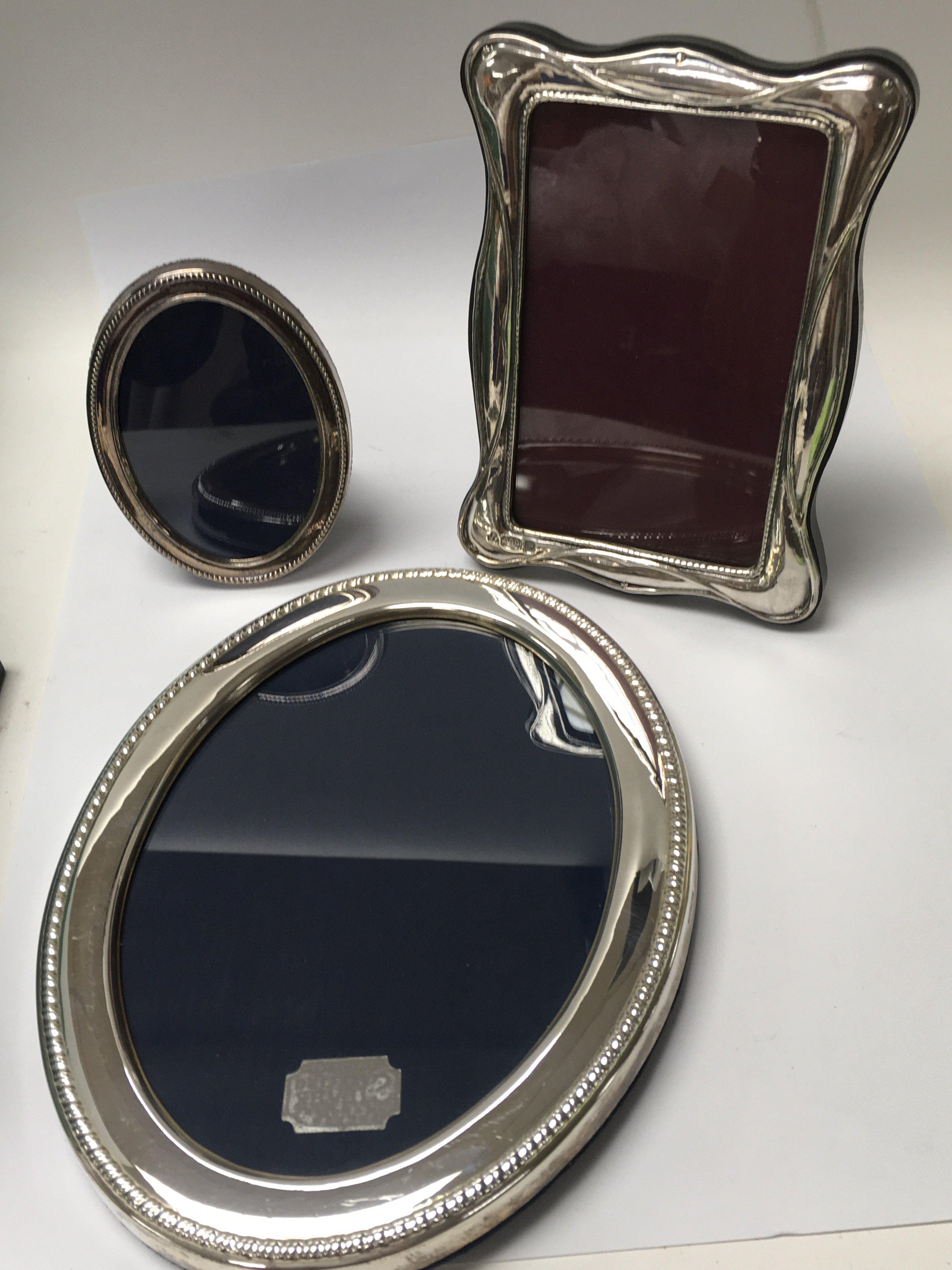 Three silver photo frames of varying sizes.