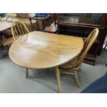 A blonde Ercol folding circular dining table together with 2 Ercole Quaker style dining chairs.