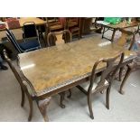 A 1920s butt walnut dining table with 4 matching dining chairs.