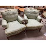 A pair of upholstered armchairs with carved walnut frames.