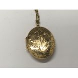 A 9ct gold oval locket with attached chain weight