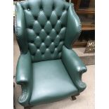 A leather button back green arm chair on cabriole