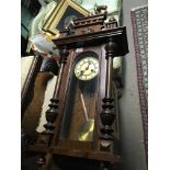 A Continental walnut wall clock with a visible pendulum in good working order