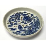 A small circular blue and white dish decorated wit