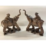 A pair of 1920s carved elephants being ridden by c