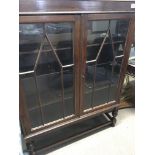 An oak bookcase with a pair of glazed doors on bul