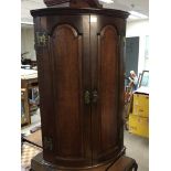 A George III oak hanging corner cabinet with arche