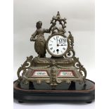 A gilt mantle clock, enamel dial with Roman numerals, flanked by a maiden. Inset with porcelain