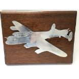 A metal war plane on a mahogany plaque.