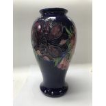 A moorcroft vase decorated with flowers and foilag