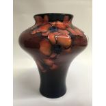 A Moorcroft vase decorated red orchids on red grou