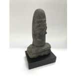 A tribal stone sculpture raised on a squared base,