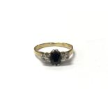 A sapphire set gold ring flanked by diamonds, meas