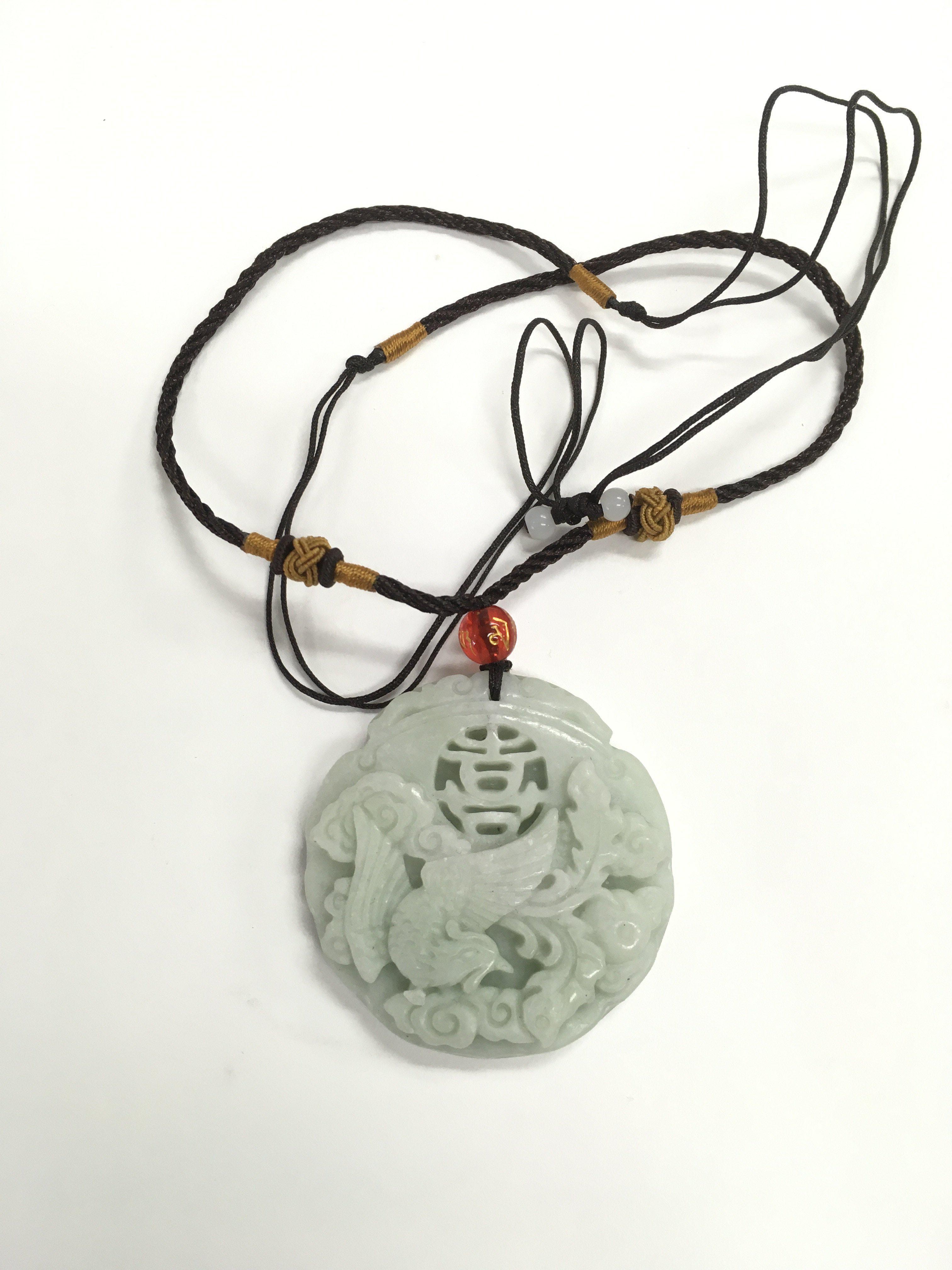 A jade style pendant suspended on a braided cord,