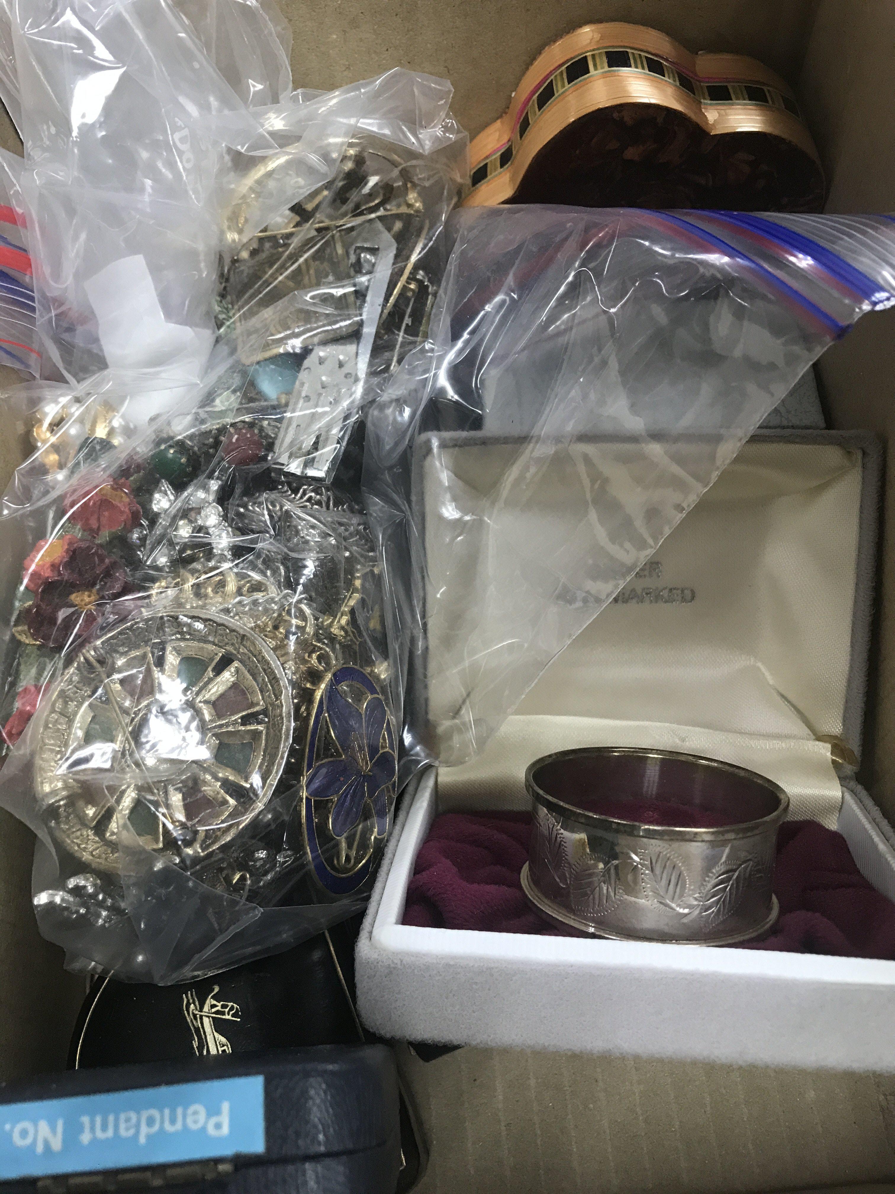 A small box of costume jewellery including brooches various and a silver napkin ring etc