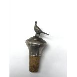 A silver bottle stopper adorned with a pheasant.