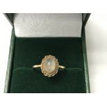 A gold ring set with a central moonstone. The appr