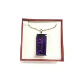 A large silver and amethyst coloured pendant on a