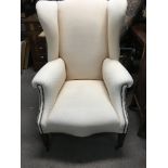 A open back wing armchair with cream upholstery on