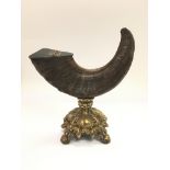 An old ram's horn snuff mull raised on an ornate brass base, approx height 22cm.
