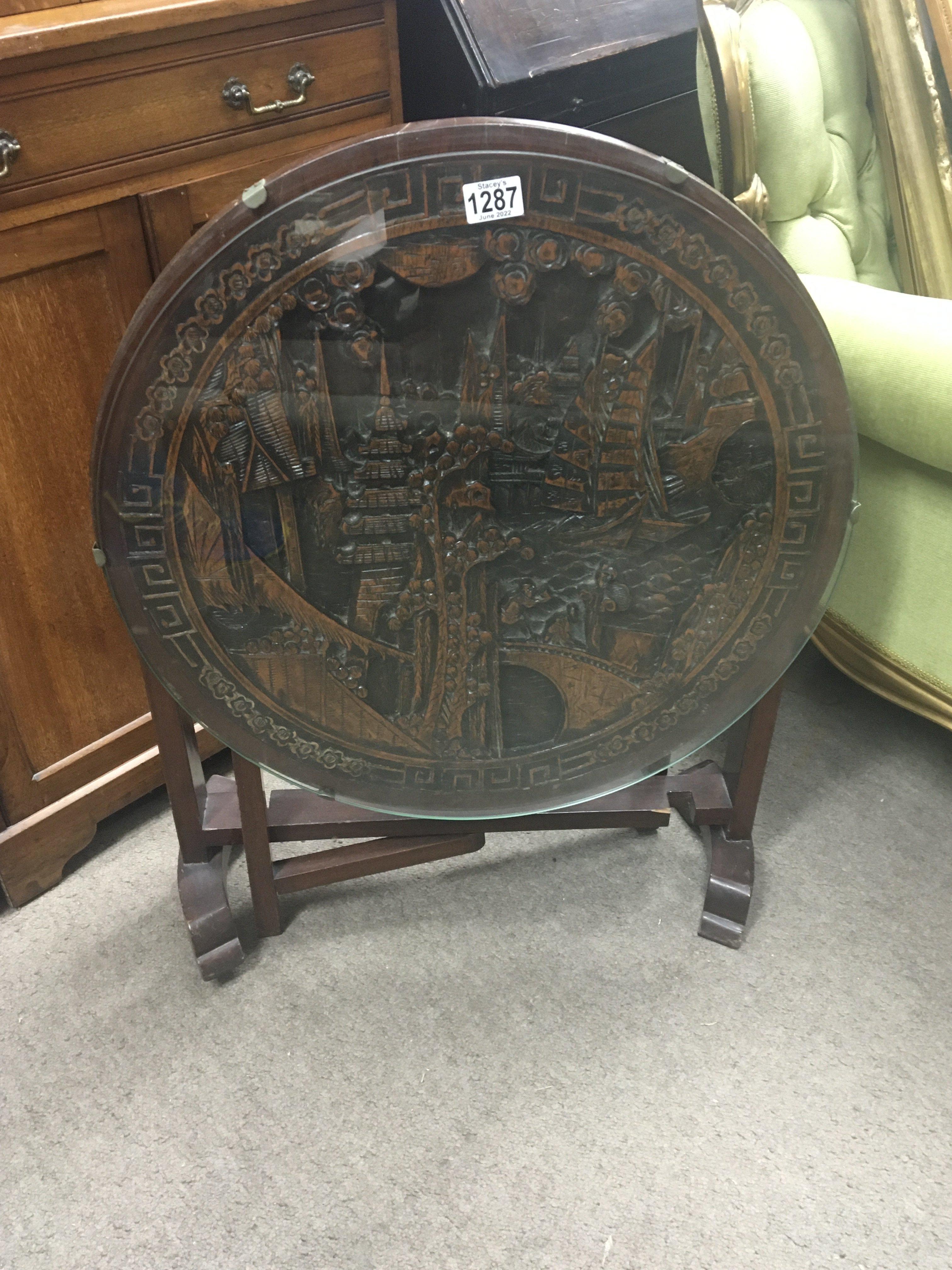 A carved hardwood oriental folding table the round