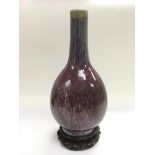 A sang de boeuf bottle vase raised on a hardwood s