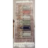 A small silk and wool hand knotted Persian prayer rug. 140 x 58cm