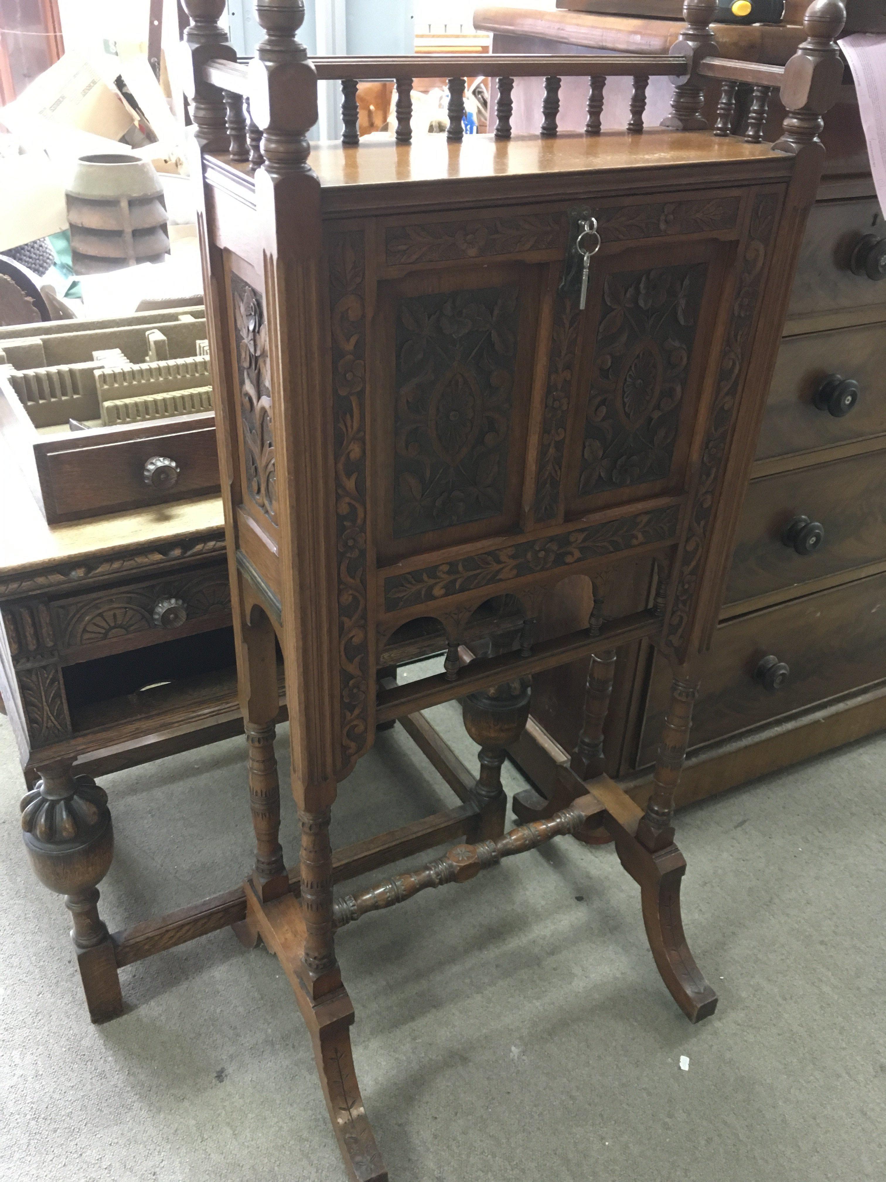 An oak bureau with heavily carved floral panels, g