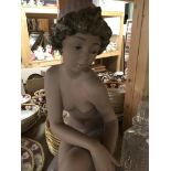 A Lladro figure of a semi nude girl seated upon a