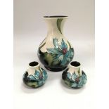 A Moorcroft vase by Emma Bosson in Sea Holly pattern together with two smaller examples, tallest