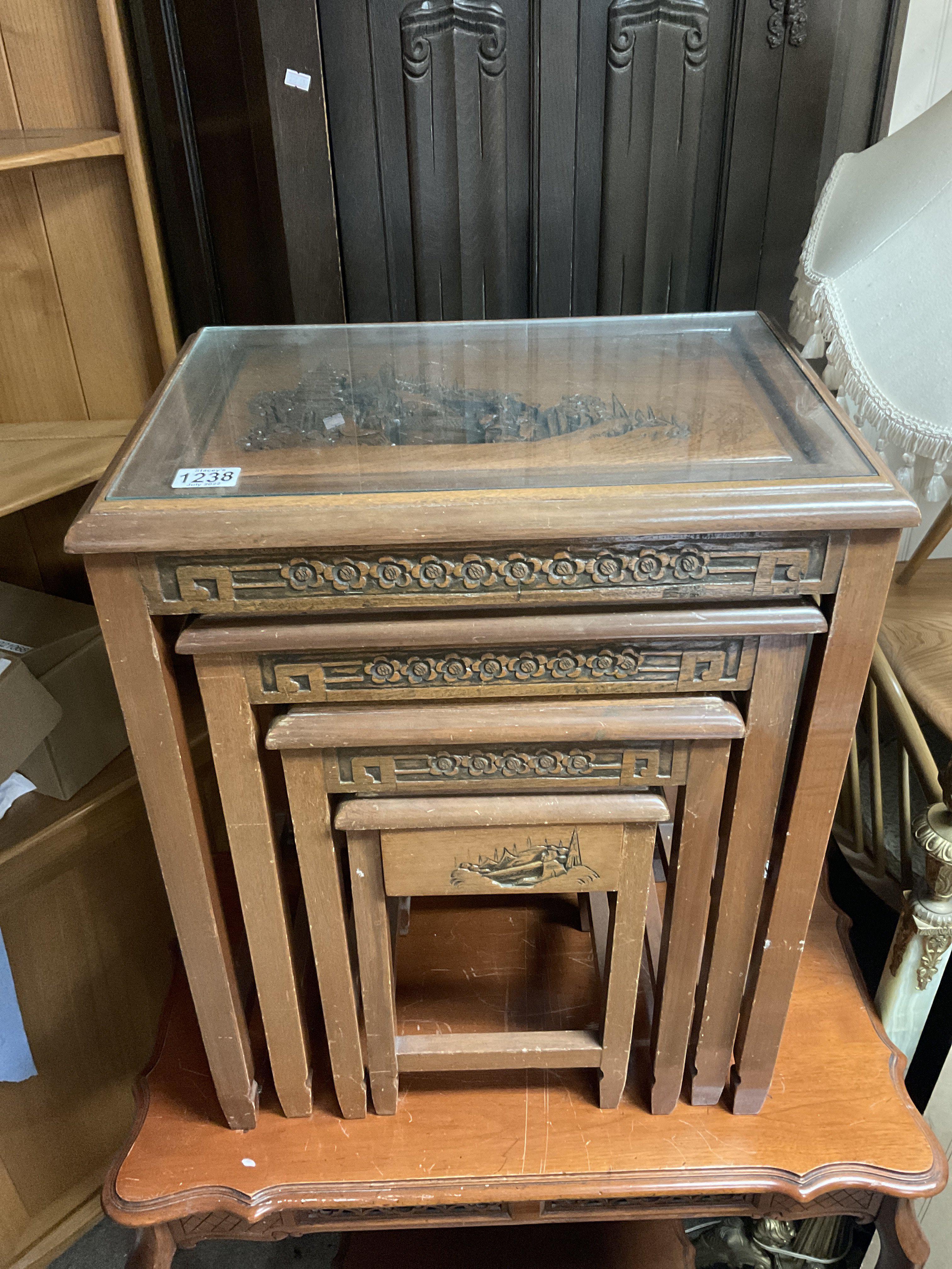 A 1930s oriental carved nest of tables with glass